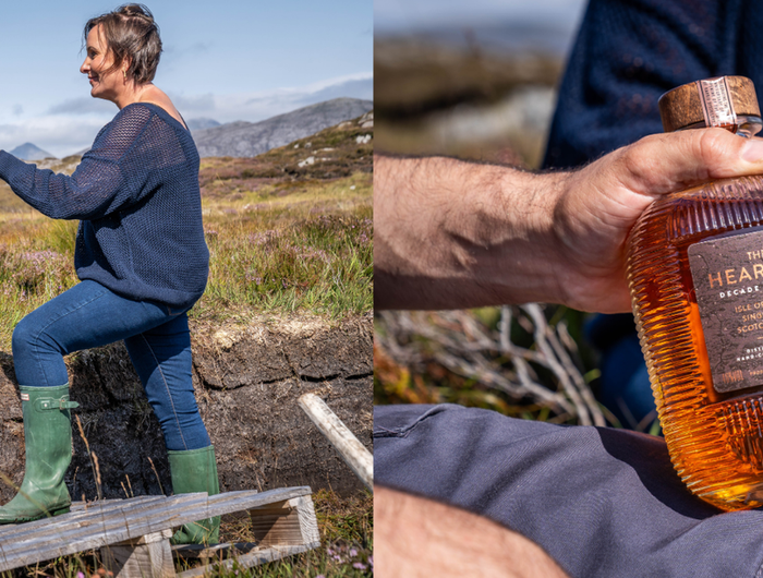 Two people sitting outdoors with a scenic background, one person holding a bottle of Kieranach whiskey.
