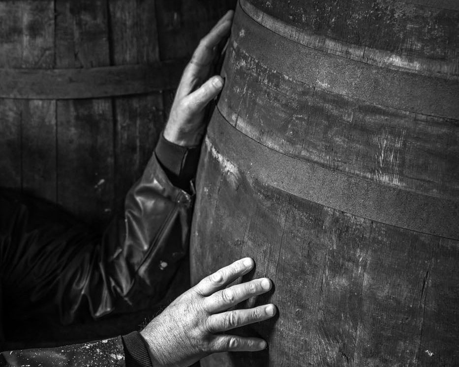 Hands carefully handling a wooden cask