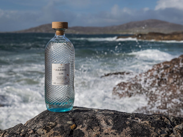 Bottle of Harris Gin on a rocky outcrop with ocean waves in the background