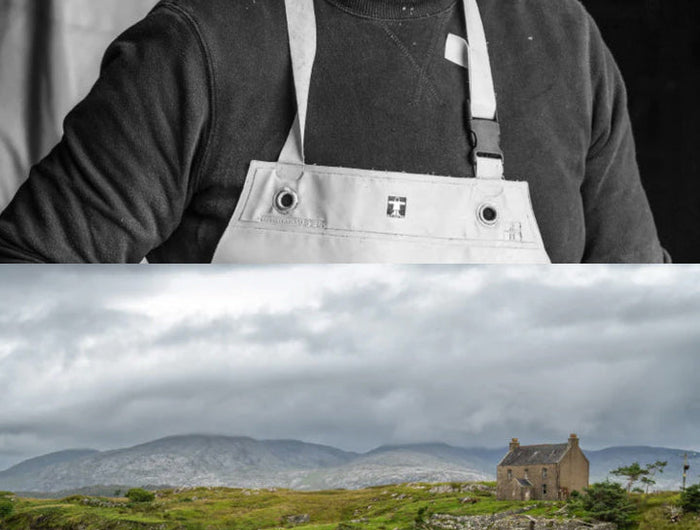 Man wearing an apron with a scenic landscape of a castle on an island in the background.