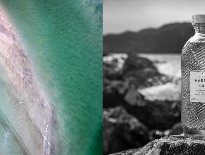 Bottle of Harris gin with a glass on a rocky outcrop by a body of water.