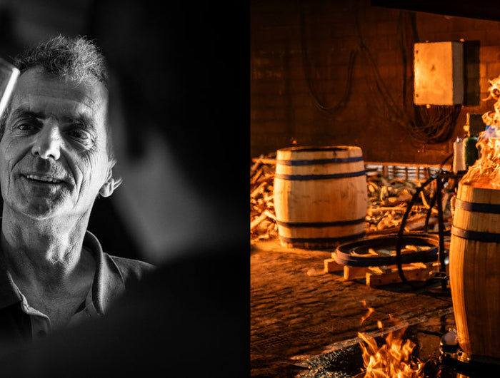 Man holding a glass of wine next to an image of barrels and flames in a cellar.